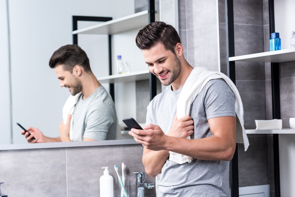 man using smartphone in bathroom - Photo, Image