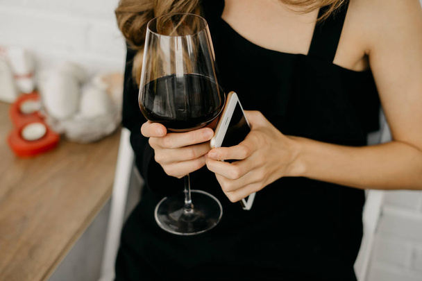 Nainen, jolla on viinin kanssa puhelin kädessä
 - Valokuva, kuva