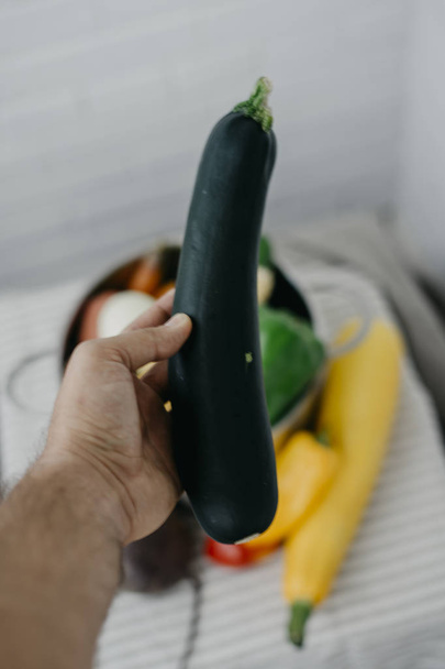 Zucchini in veganer Männerhand - Foto, Bild