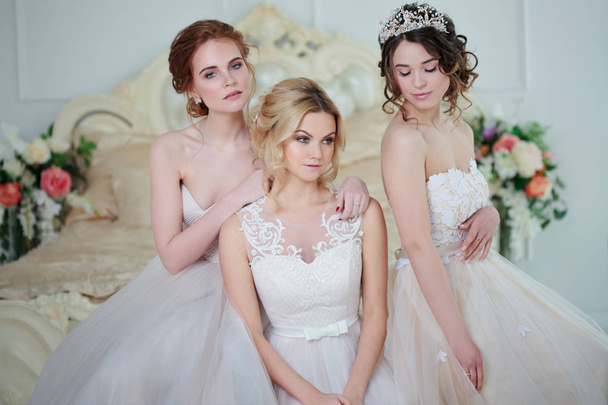 Three girls in wedding dresses. Beautiful delicate girls in the Bridal salon - Fotó, kép