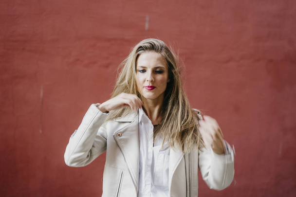 Woman in white jacket near red wall - Foto, Imagem