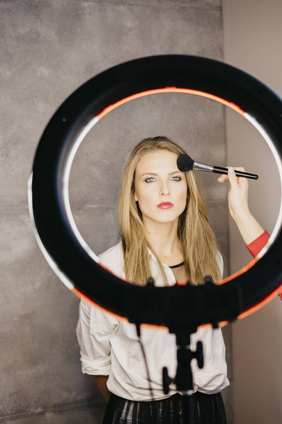 Woman in photo studio applying makeup - Foto, imagen