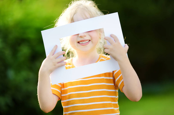 little girl holding white frame - 写真・画像