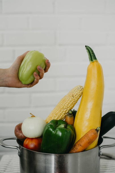 Hand mit Gemüse in einem metallenen Topf - Foto, Bild