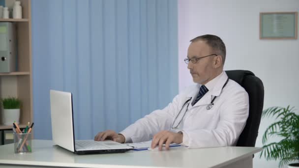 Doctor studying treatment methods on laptop, surprising by innovative approach - Video