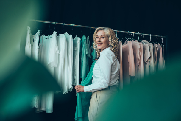 улыбающаяся женщина выбирает одежду в магазине
 - Фото, изображение