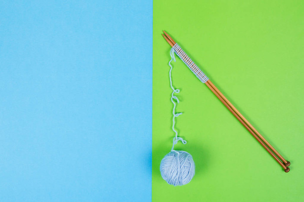 Голубая пряжа шар и вязальные спицы на красочном фоне
 - Фото, изображение