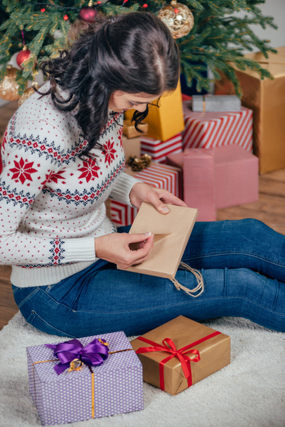 жінка розпаковує різдвяний подарунок
 - Фото, зображення