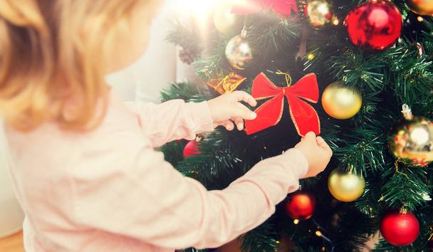 close up of little girl decorating christmas tree - 写真・画像