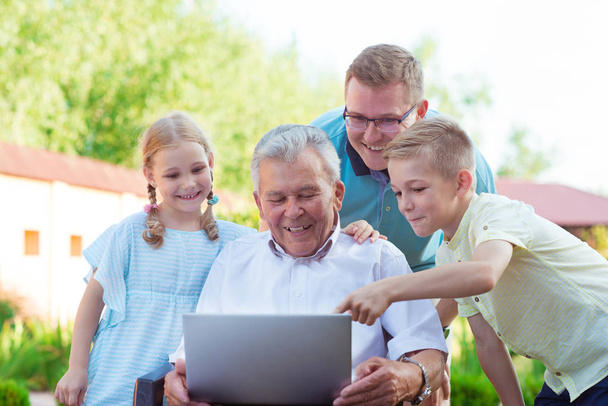 Happy family with grandfather during internet talking on laptop - Foto, afbeelding