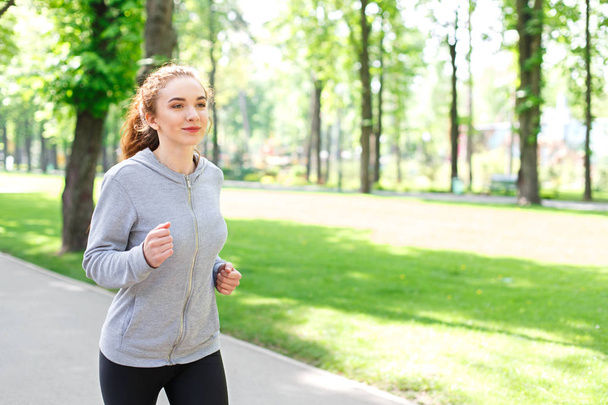Young woman running in green park, copy space - Φωτογραφία, εικόνα
