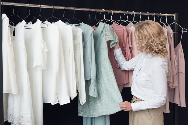 Žena vybírá oblečení v obchodě s oblečením - Fotografie, Obrázek