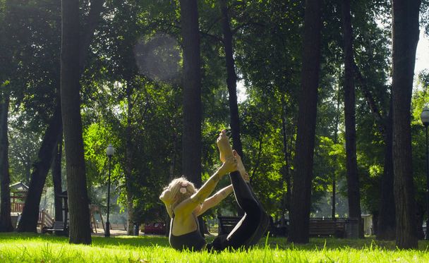 Young woman doing yoga exercises in the park - Photo, Image