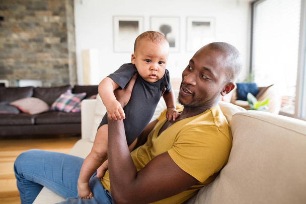 Jonge Afro-Amerikaanse vader die zijn zoontje in de armen - Foto, afbeelding