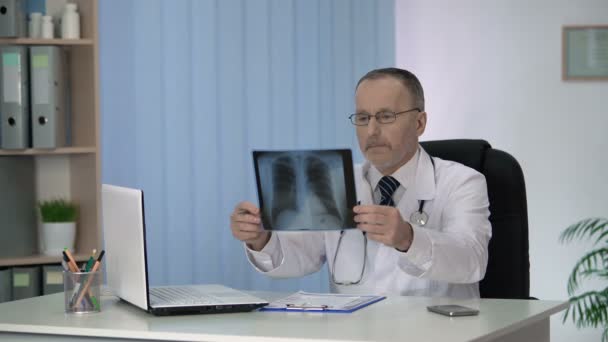 Experienced radiologist carefully examining and describing X-ray image of lungs - Кадры, видео