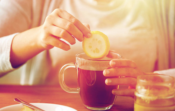 close up of woman adding lemon to tea with honey - Φωτογραφία, εικόνα