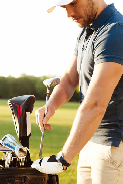 Young focused man golfer taking out the golf club - Фото, изображение