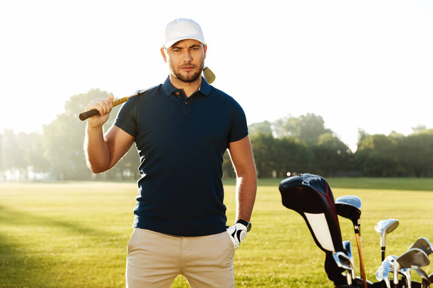 Handsome confident male golfer standing with golf club - Foto, Bild
