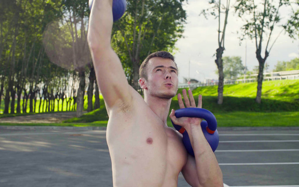 A young man is lifting dumbbells - Фото, зображення