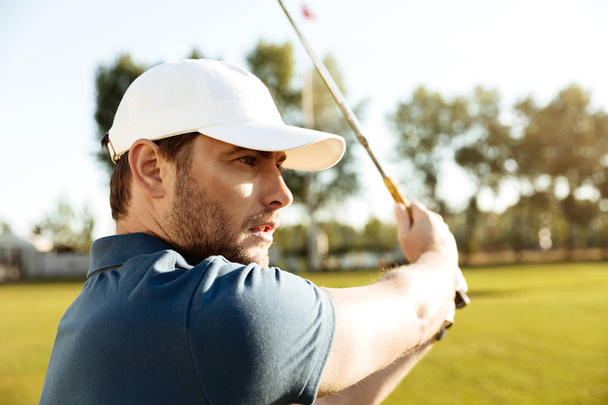 Close up of a young male golfer hitting a fairway shot - Fotó, kép