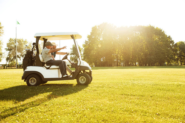 Two male golfers driving in a golf cart - Zdjęcie, obraz