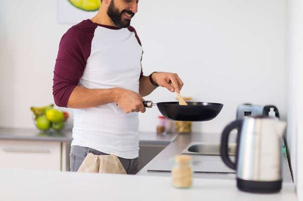man with frying pan cooking food at home kitchen - Valokuva, kuva