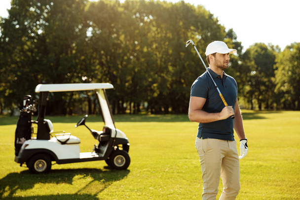 Young male golfer with golf club standing - Foto, Bild