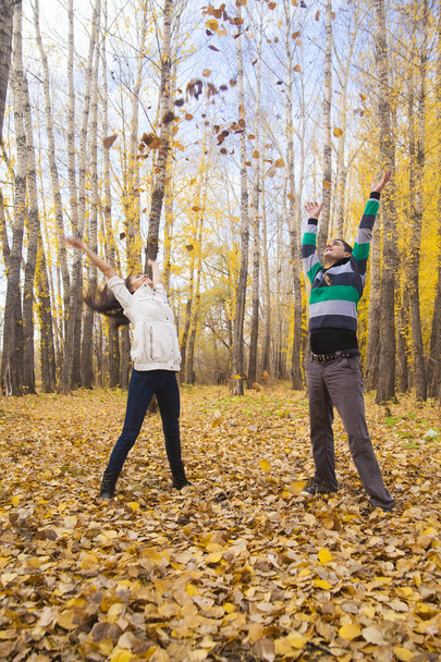 Young adult  happy couple throwing up autumn leaves in the air  - Photo, image