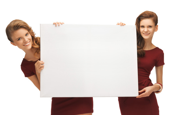Two teenage girls in red dresses with blank board - Фото, изображение