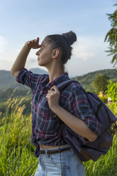 Хипстерская молодая девушка с рюкзаком наслаждается закатом на вершине горы. Туристический путешественник на фоне долины пейзаж макет
. - Фото, изображение