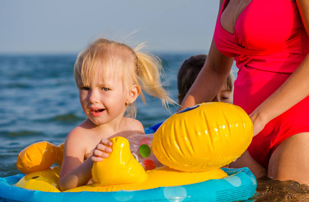 Menina de três anos nada no mar com sua mãe sentada no anel de borracha
. - Foto, Imagem