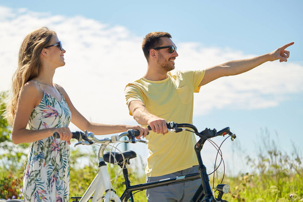 счастливая молодая пара с велосипедами на открытом воздухе
 - Фото, изображение