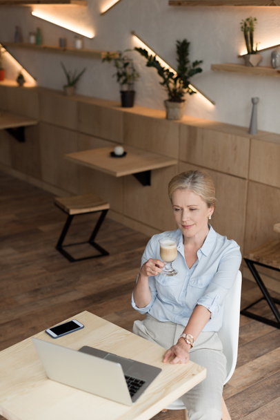 woman drinking coffee and using laptop - Fotografie, Obrázek