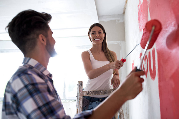 Lovely smiling happy couple painting new home - Foto, Imagem