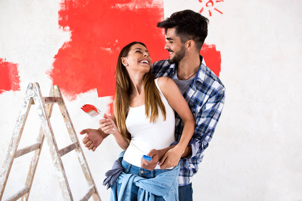 Young happy couple painting walls in their new house - Foto, Imagen