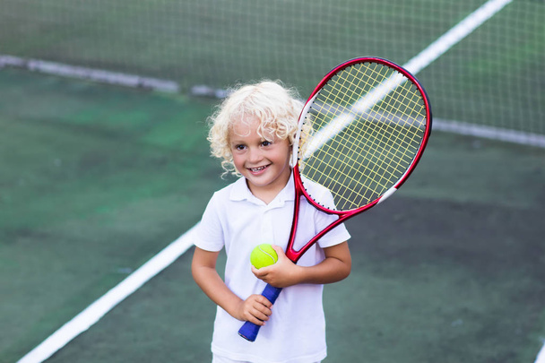 Child playing tennis on outdoor court - Valokuva, kuva