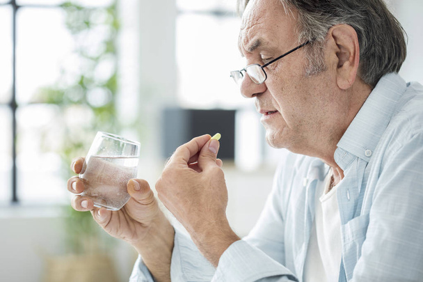 Old man taking a pill - Fotografie, Obrázek