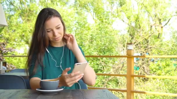 Nuori nainen soittaa kännykällä istuessaan yksin kahvilassa vapaa-ajalla. Houkutteleva nainen söpö hymy ottaa puhuminen keskustelun matkapuhelin kun levätä kahvilassa
 - Materiaali, video