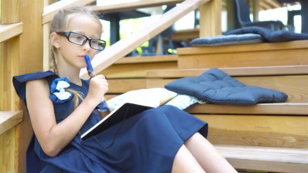 entzückendes kleines Schulmädchen mit Zetteln und Bleistiften draußen. Zurück zur Schule. - Filmmaterial, Video