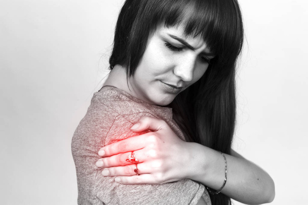 Young woman with shoulder pain  black and white with red accent - Photo, Image