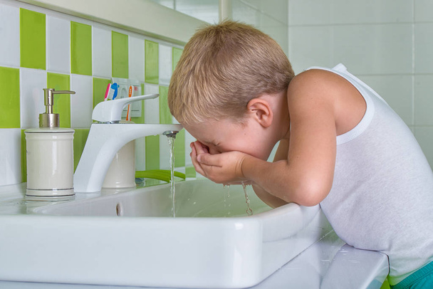 Boy wash the face in the bathroom.The beginning of a new day - Zdjęcie, obraz