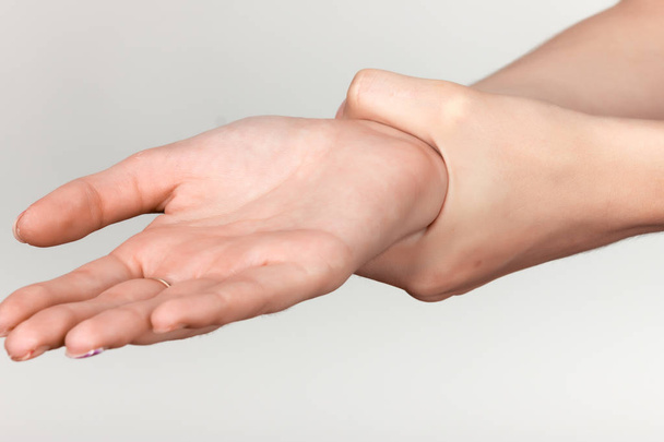 Close-up. Vrouw met pijnlijke pols in haar hand - Foto, afbeelding