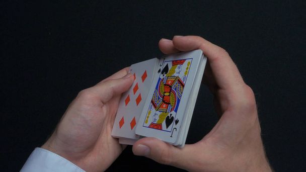 Gra w pokera - tasowania kart. Mans ręce shuffing karty. Z bliska. Mans ręce tasowania kart do gry. Dealerzy ręce tasowania kart podczas gry w pokera - Zdjęcie, obraz