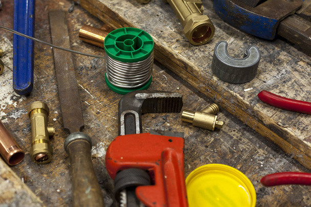 Adjustable wrench and plumbing fittings on a work bench - Photo, Image