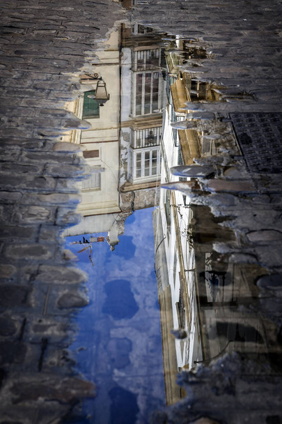 Bâtiments reflétés dans une flaque d'eau dans la rue, Andalousie, Espagne
 - Photo, image