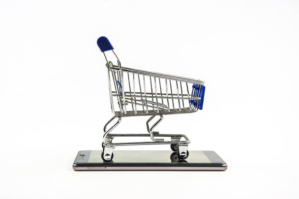 teléfono inteligente con carrito de compras sobre fondo blanco, Medios de compra
 - Foto, Imagen