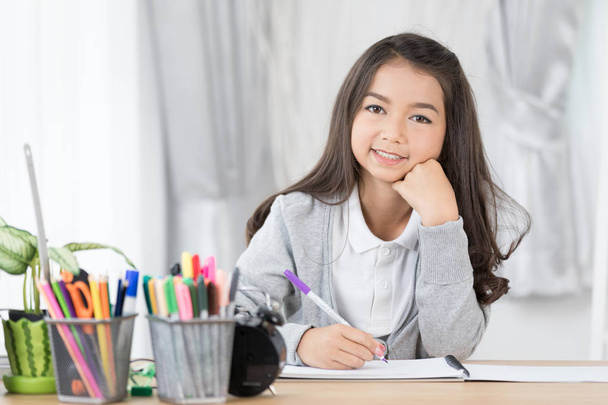 Menina asiática bonito escrever algo em papel com lápis de cor
 - Foto, Imagem