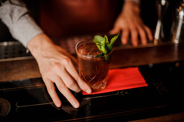Barman holds a cocktail with mint in his hand. No face - 写真・画像
