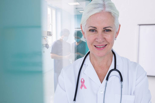 Doctor with breast cancer awareness ribbon - Fotoğraf, Görsel