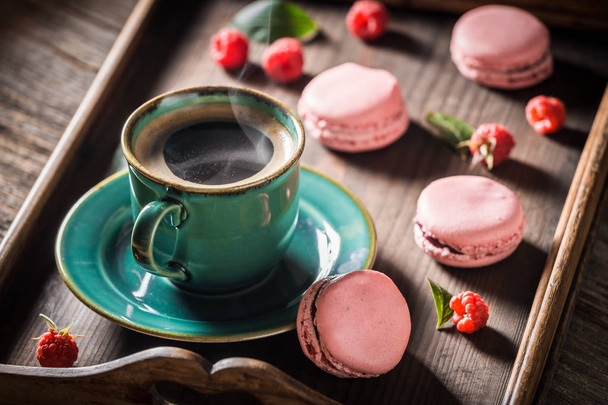 Sweet pink macaroons served with hot coffee - Фото, изображение